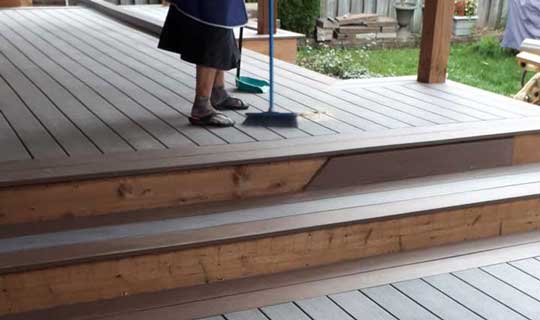 Grandma sweeping newly constructed backyard porch